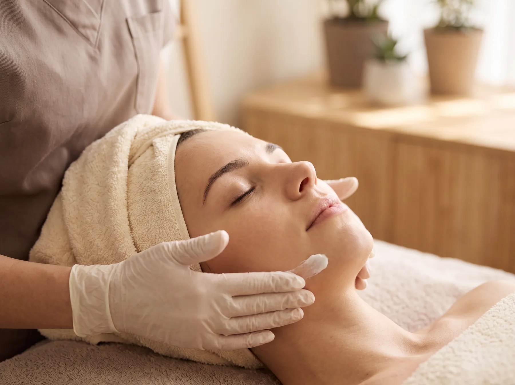 A guest with eyes closed receiving a custom facial in a sunlit treatment room